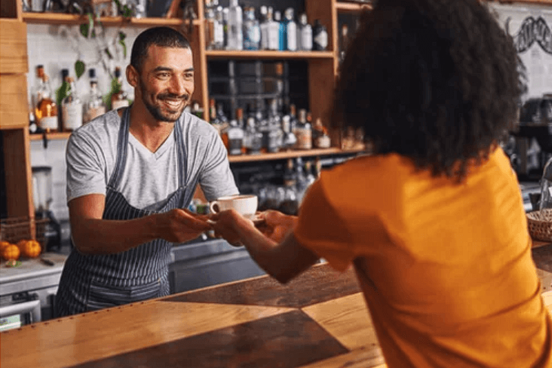 a barista handing a customer a coffee